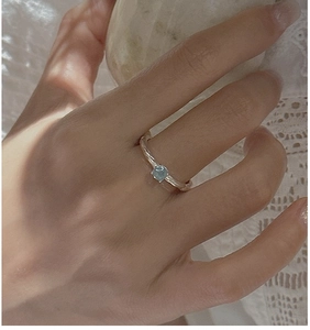 Detail of S925 silver ring with blue aquamarine stone and hammered texture on finger