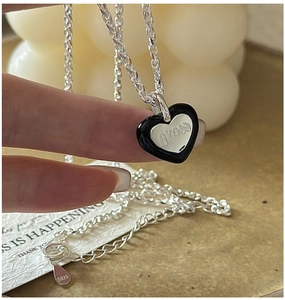 Gros plan du pendentif cœur en argent S925 avec émail noir et gravure 'grow' sur la chaîne