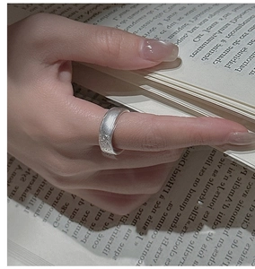 Macro detail of silver ring with hammered texture worn by a model on book background