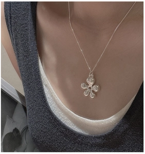 Close-up of S925 sterling silver hollow flower pendant on a thin chain worn by a model