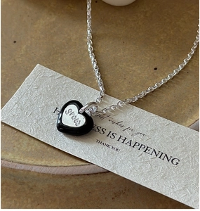 Gros plan du pendentif cœur vintage avec émail noir et gravure STORY sur chaîne en argent