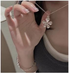 Close-up of polished silver hollow flower pendant on model showing sleek metallic texture