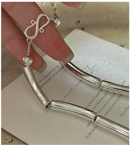 Macro detail of S925 silver tube necklace featuring a unique S-shaped artistic hook clasp