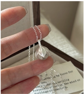 Détail du pendentif bouton de fleur en argent mat sur une chaîne fine