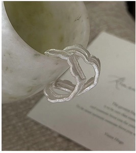 Close-up of S925 sterling silver earrings with textured wave design and brushed finish