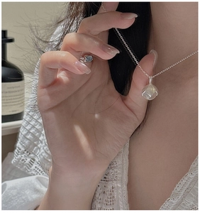Détail du collier et de la bague en argent fleur de muguet avec pierre de lune sur modèle