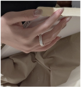 Détail de la bague en argent sterling S925 avec texture tissée portée au doigt tenant un livre