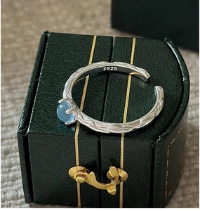 Macro detail of S925 silver ring with hammered texture and light blue gemstone