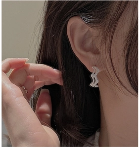 Close-up of S925 sterling silver wavy earrings with brushed texture on female model