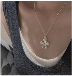 Close-up of a minimalist S925 sterling silver hollow flower pendant on a model neck