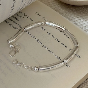Minimalist S925 sterling silver hollow tube bracelet displayed on a vintage book