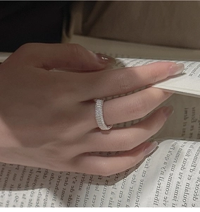 Gros plan d'une bague en argent 925 torsadé sur la main avec un décor de livre vintage