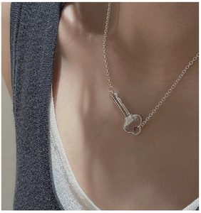 Macro shot of silver key pendant with FOREVER engraving on a minimalist chain necklace