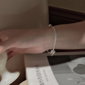 S925 sterling silver clover charm bracelet with sparkling beads on a vintage book background