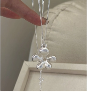 Macro detail of 3D hollow silver flower pendant on delicate sterling silver chain