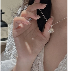 Détail du collier pendentif bouton de fleur en argent S925 et bague assortie sur modèle