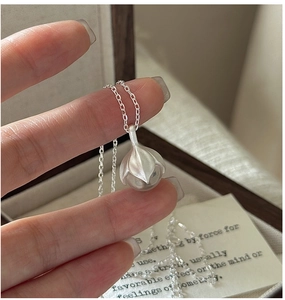 Gros plan détaillé du collier pendentif bourgeon en argent mat avec perle de cristal