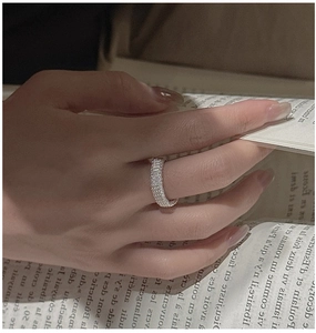 Détail d'une bague en argent S925 à texture tressée portée à la main près d'un livre