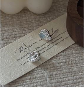 Macro detail of S925 silver stud earrings with aquamarine stone and hammered texture
