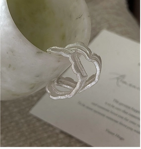 Macro shot of silver wave-textured earrings showing detailed brushed metal craftsmanship