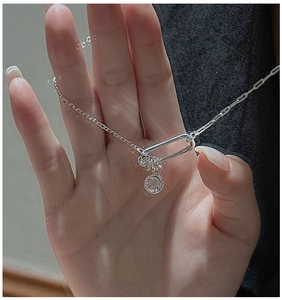 Detail of S925 silver paperclip chain necklace with safety pin pendant and zircon charm