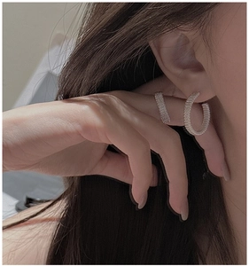 Close-up of S925 sterling silver hoop earrings with woven texture on a female ear