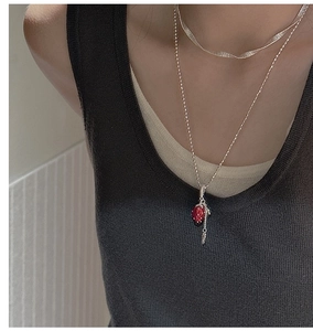 Detail of layered S925 sterling silver necklaces with red strawberry pendant and flat snake chain