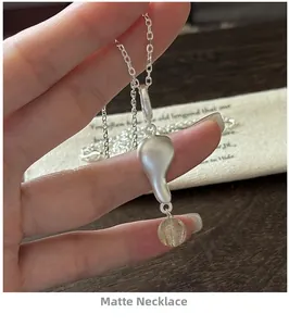Dettaglio della collana in argento opaco con pendente a ciottolo e cristallo giallo