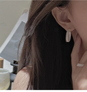 Close-up of woven silver mesh earrings and ring set on model with minimalist style