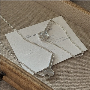 Detailed macro of S925 sterling silver key necklace with Love Me engraving on fabric