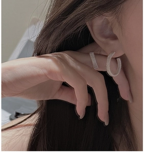 Macro shot of S925 sterling silver C-shaped earrings with hand-woven wire texture on ear