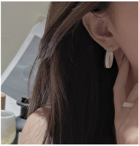 Detail of handcrafted silver wire-wrap hoop earrings and ring set on female model
