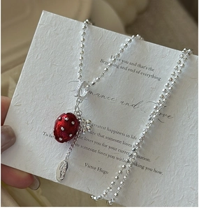 Detail of S925 silver necklace featuring a red strawberry pendant with a tiny flower