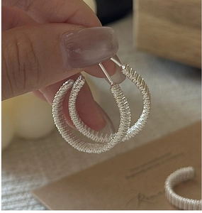 Close-up of silver S925 sterling silver hoop earrings with hand-wound wire texture details
