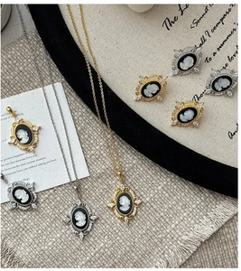 Macro detail of vintage cameo pendants and earrings with cubic zirconia on textured fabric