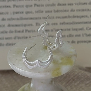 Elegant S925 sterling silver hoop earrings with wavy texture on white marble display