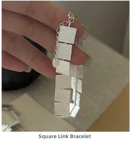 Close-up of S925 sterling silver square link bracelet with brushed metal texture and hand holding