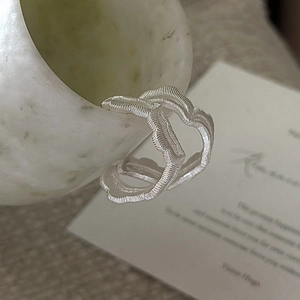 S925 sterling silver earrings with irregular wave texture hanging on a marble ceramic cup