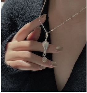 Dettaglio della collana in argento S925 con perla di citrina su sfondo di maglione nero