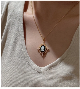 Detail of vintage cameo pendant necklace with cubic zirconia on a ribbed knit sweater