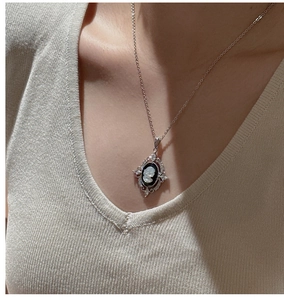 Macro shot of silver cameo pendant necklace with female relief on light knitwear