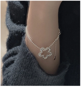 Dettaglio del bracciale a fiore in argento S925 indossato su un maglione grigio scuro