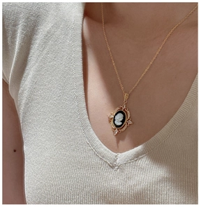 Detail of vintage cameo pendant with silhouette on model wearing beige knit top