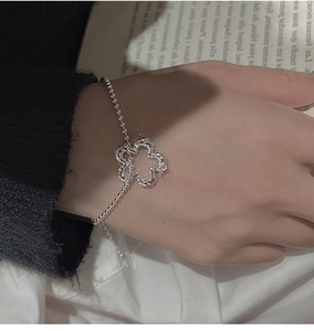 Macro di bracciale in argento S925 con ciondolo a fiore traforato indossato sul polso