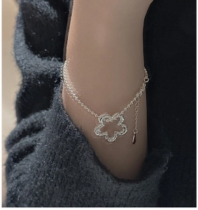 Dettaglio del bracciale in argento S925 con fiore traforato e catena a sfere al polso