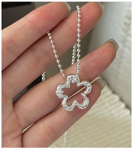 Macro detail of S925 silver flower pendant with lava texture and zircon on bead chain