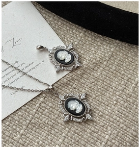 Detailed view of cameo pendant with zircon inlay and silver necklace on elegant prop card