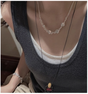 Detail of layered S925 sterling silver necklace set with colorful bead pendants on model
