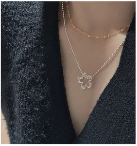 Detail of layered S925 silver floral pendant necklace on model with black fabric background