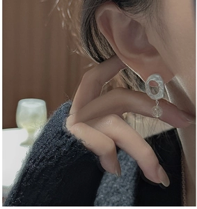 Macro shot of silver hammer-textured hoop earrings with clear round bead on model